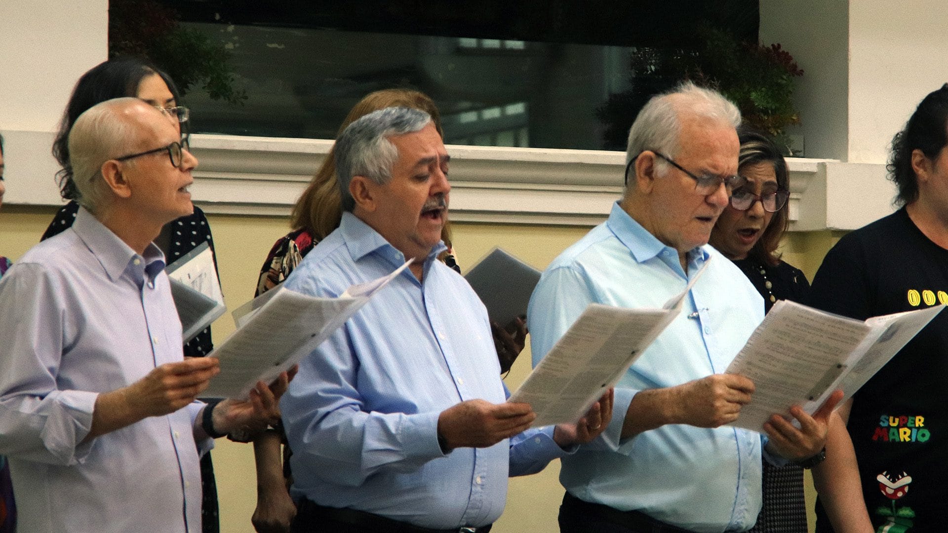Coristas masculinos do Coro Rutter cantando com partituras